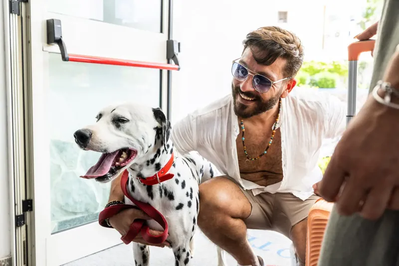 Ospite accovacciato accanto al suo dalmata all'ingresso dell'hotel