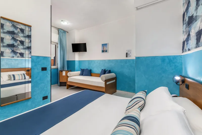 Camera con letto, divano letto e pareti azzurre vista dal letto