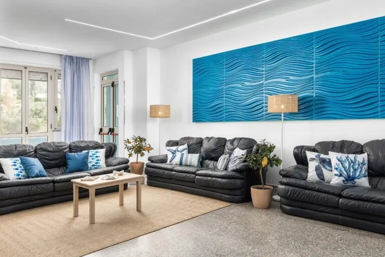 Sala comune con divani in pelle nera, cuscini blu e pannello azzurro a onde
