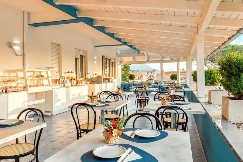 Sala colazione sotto il porticato con tavoli apparecchiati e buffet