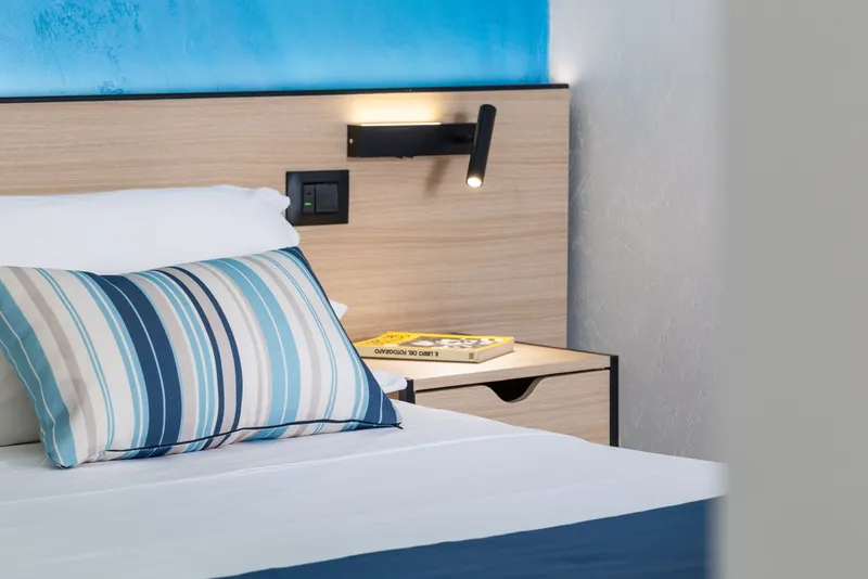 Cuscino a righe blu e testiera in legno con luce di lettura
