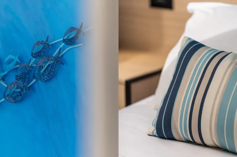 Parete azzurra con pesci decorativi e cuscino a righe sul letto