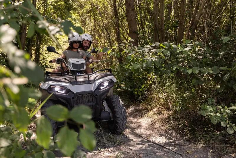Coppia in quad lungo un sentiero nel bosco